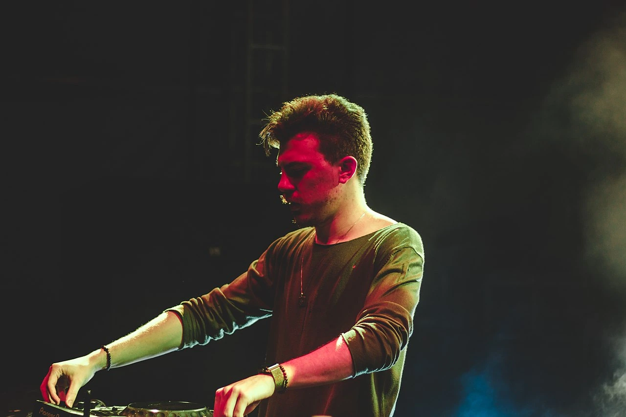 Zerb performing DJ set on stage under dramatic red and green lighting.